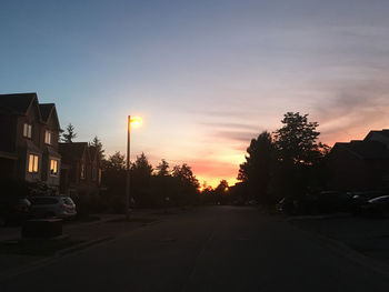 Street amidst buildings against sky during sunset