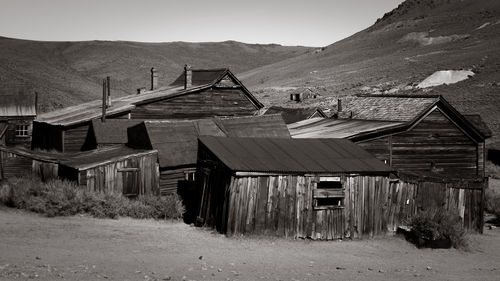 Old wooden house on field by mountains against sky