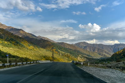 Road by mountains against sky