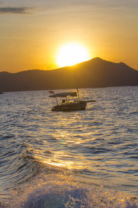 Silhouette boats in sea against sky during sunset