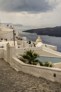 High angle view of houses by sea against cloudy sky