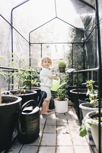 Blond girl watering plans in greenhouse