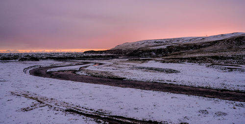 Scenic view of snow covered land against sky during sunset