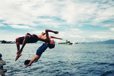 Man jumping in sea against sky