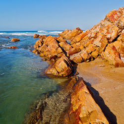 Rock formation in sea against clear blue sky