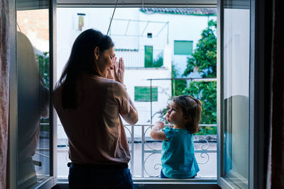 Mother and daughter applauding from the window of the house very happily