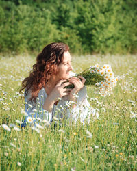 Side view of young woman sitting on grassy field