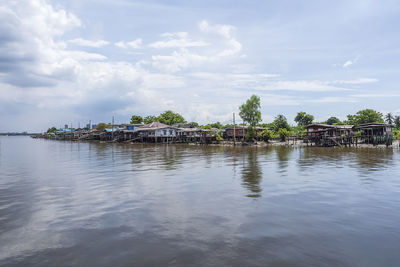 Scenic view of river by buildings against sky