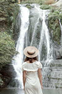 Rear view of woman standing against waterfall