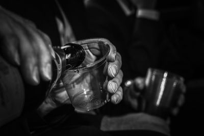 Close-up of hand pouring drink in drinking glass at darkroom