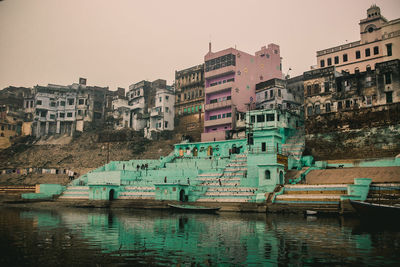 Buildings by lake against sky in city