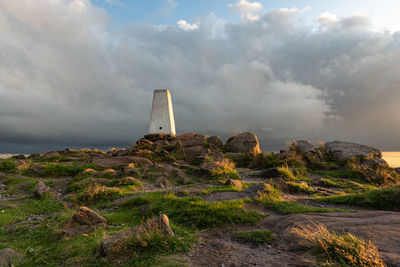 Lighthouse amidst rocks on land against sky