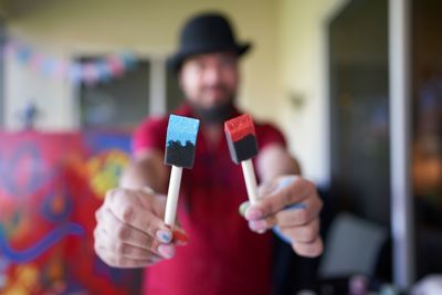 Portrait of man holding hat standing against blurred background