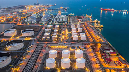 High angle view of illuminated factory by sea