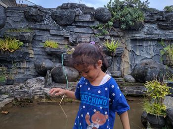 The girl is playing on the edge of the fish pond with a beautiful scenery background