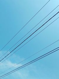 Low angle view of power cables against clear sky