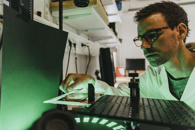 Scientist adjusting human brain slide on microscope while examining at laboratory