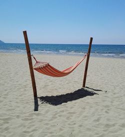 Deck chairs on beach against clear sky