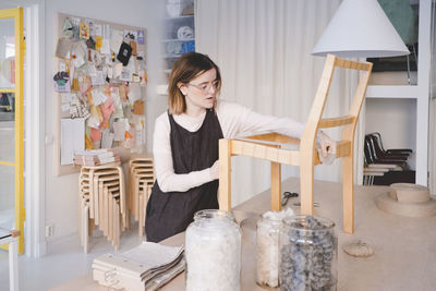 Young female upholstery worker working on chair in workshop