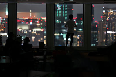 Rear view of people standing in city at night