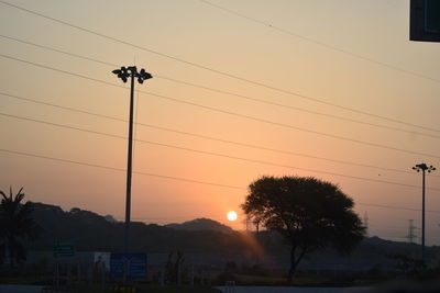 Low angle view of silhouette electricity pylon against sky during sunset