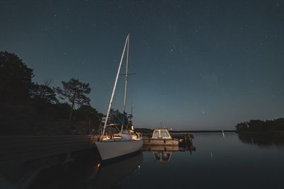 Sailboat moored on lake against sky at night