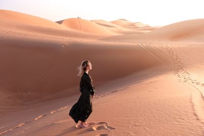 Full length of woman standing on sand dune at desert