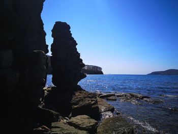 Rock formation on beach against clear blue sky