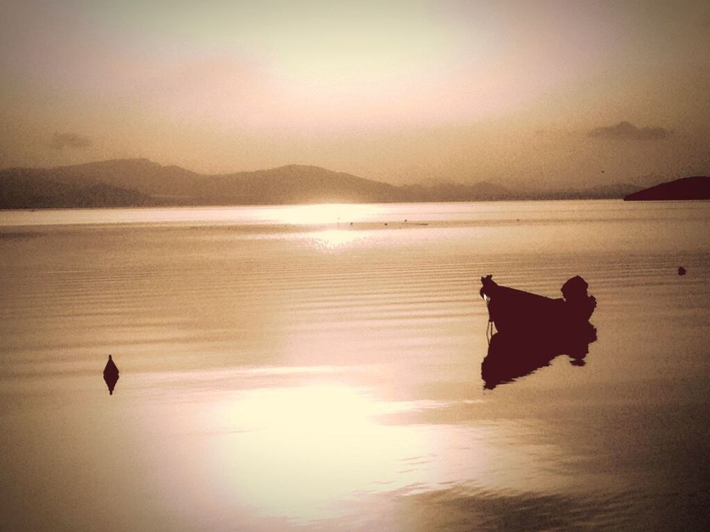 SILHOUETTE OF TWO PEOPLE ON CALM SEA
