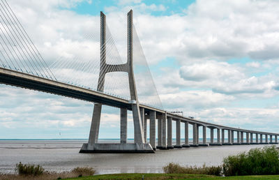 Vasco da gama bridge over river against cloudy sky