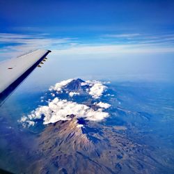 Aerial view of aircraft wing over landscape against sky