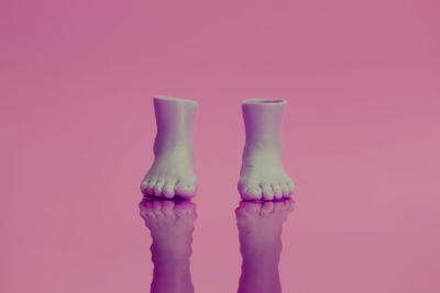 Low section of person standing against pink background