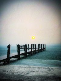 Wooden posts in sea against sky