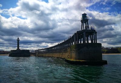 Lighthouse by sea against sky