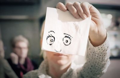 Optical illusion of woman holding anthropomorphic face on tissue