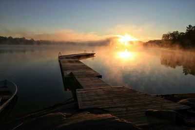 Pier on lake at sunset