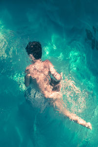 High angle view of naked boy swimming in sea