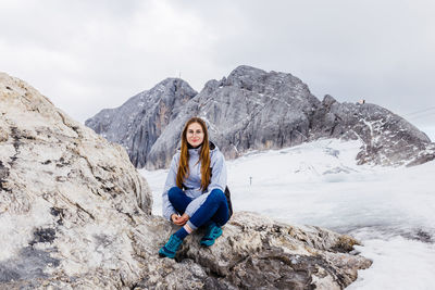 Young millennial girl enjoys the views of the alps standing on glacier