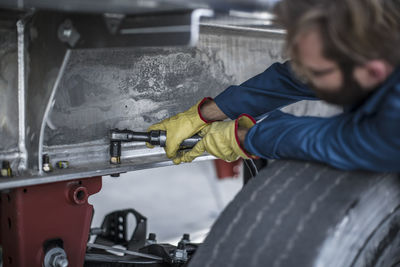 Mechanic tightening nuts on steel container