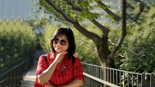 Portrait of a smiling young woman standing against trees