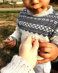 Close-up of boy holding hands on field