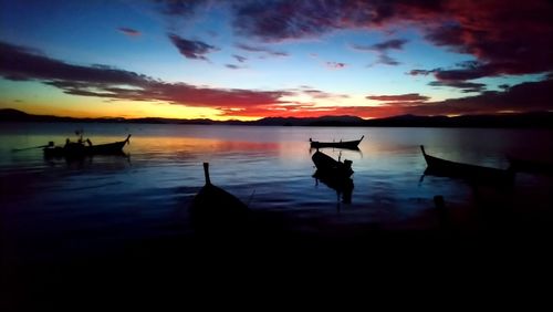 Silhouette wooden posts in lake against sky during sunset