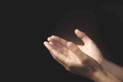 Close-up of person hand against black background