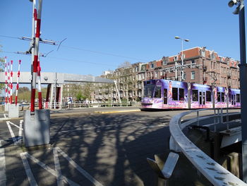 Cars on street by buildings against clear sky