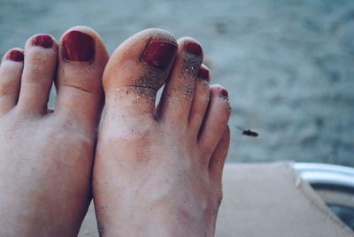 Low section of woman relaxing on chair at beach