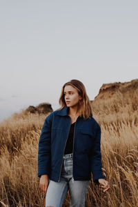 Young woman standing on field against clear sky