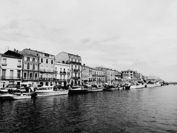 Boats moored in canal by buildings against sky