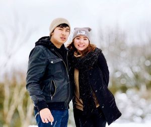 Portrait of friends wearing warm clothing during snowfall