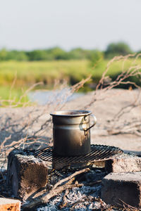 Coffee pot warming up on camping bonfure