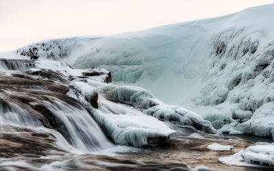 Scenic view of waterfall against sky during winter